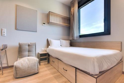 毕尔巴鄂Livensa Living Studios Bilbao的一间卧室设有一张床、一个窗口和一把椅子