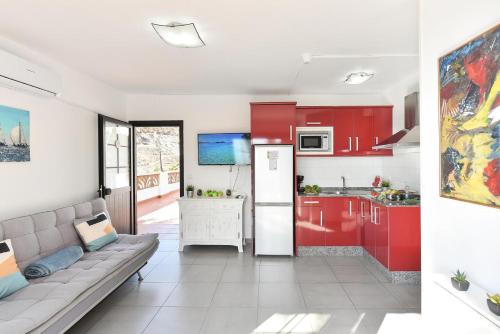 莫甘Beach Apartment in Playa del Cura 323的一间厨房,内设红色橱柜和一张沙发