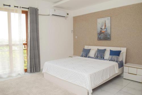 蒙巴萨THE NEST, Beachfront Serviced Apartment in Nyali - with Panoramic Ocean view的卧室配有带蓝色枕头的大型白色床