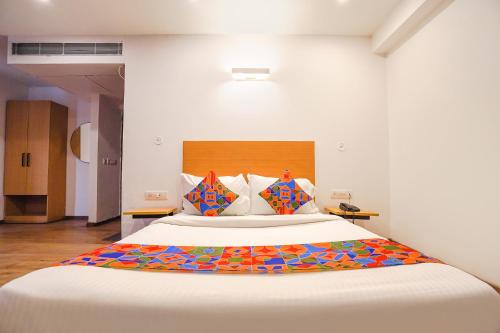 Vibhuti KhandFabHotel Ramayana的卧室配有一张带彩色枕头的大型白色床。