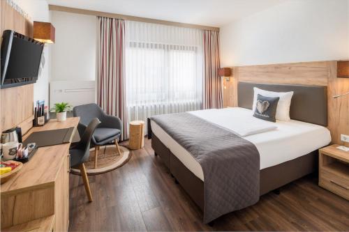 埃斯林根Neo Hotel Linde Esslingen的酒店客房设有一张床、一张书桌和一台电视机。