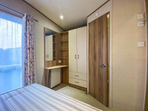 惠茨特布尔Lovely 6 Berth Caravan With Decking And Wifi In Kent, Ref 47017c的一间卧室配有一张床和一个衣柜及一扇门