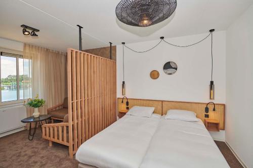 托尔恩Parc Maasresidence Thorn Lake View Hotel Rooms的一间卧室配有一张大床和一把椅子