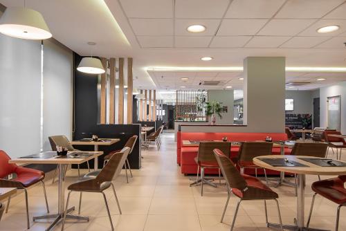 萨尔瓦多Best Western Salvador Hangar Aeroporto的一间带桌椅和红色沙发的餐厅