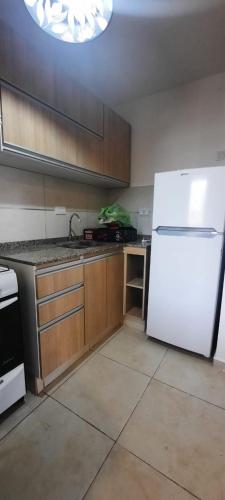 里奥夸尔托Rio Apart Imperio的厨房配有白色冰箱和木制橱柜。