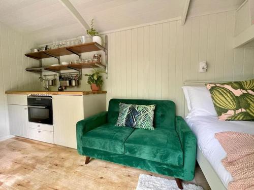 UplymeCosy Shepherds Hut Lyme Regis的带厨房的客房内的绿色沙发