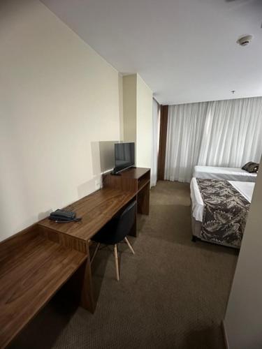 塔瓜汀加HOTEL condomínio EDIFÍCIO COMFORT TAGUATINGA FLAT的酒店客房配有书桌和床。
