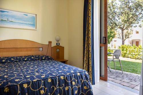 圣伊西多罗萨兰托村蓝色酒店的一间卧室设有一张床和一个滑动玻璃门