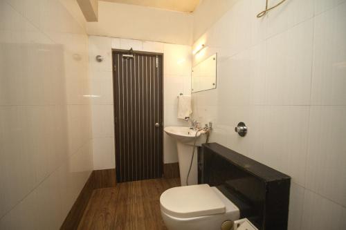西里古里Hotel Sundaram Palace的白色的浴室设有卫生间和水槽。