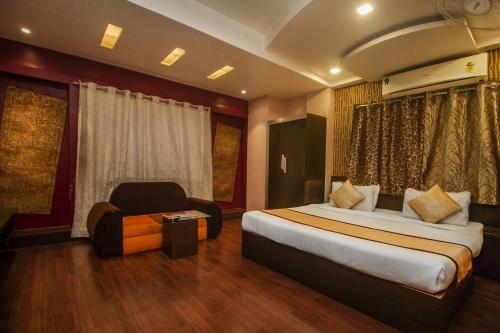 西里古里Hotel Sundaram Palace的配有一张床和一把椅子的酒店客房