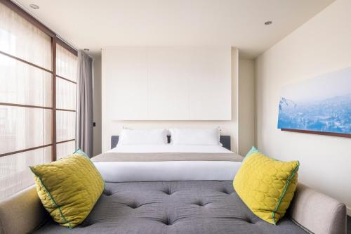 巴塞罗那六十二号酒店的一间卧室配有一张床和一张带黄色枕头的沙发。