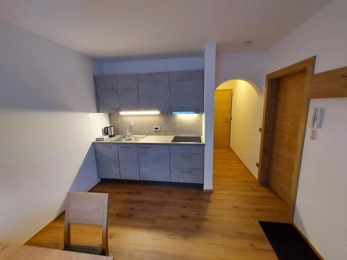 圣坎迪朵Appartements Schäfer的厨房铺有木地板,配有白色橱柜。