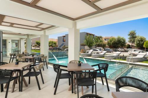 埃亚玛琳娜奈奇多Elia Agia Marina Resort的一个带桌椅的户外庭院和一个游泳池