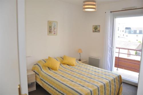 佩罗斯-吉雷克Bel appartement 2 chambres au centre-ville de PERROS-GUIREC - Ref 926的一间卧室配有一张带黄色枕头的床和一扇窗户