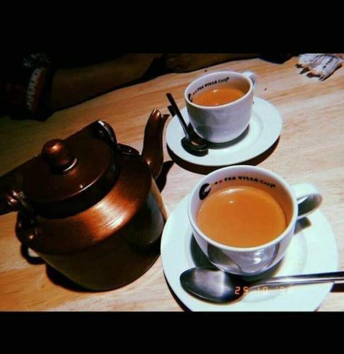 木尔坦Motel Ambassador Multan的桌子上放两杯茶和茶壶