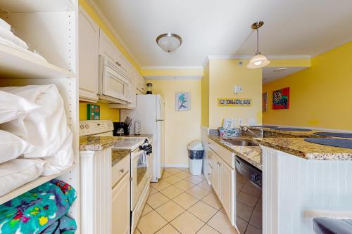 大洋城Makai 404的厨房配有白色橱柜和白色冰箱。