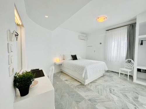 帕罗奇亚Paradiso Boutique的白色的卧室配有白色的床和一张桌子