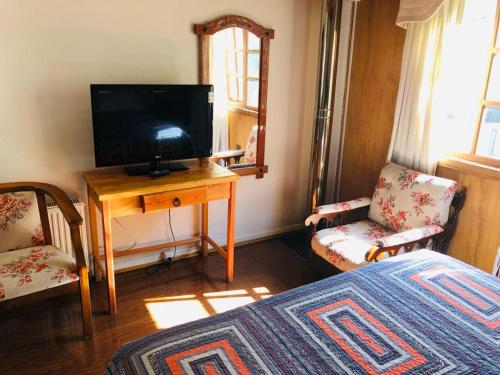 特木科Hostal Collins House的一间卧室配有电视和一张桌子及一张床