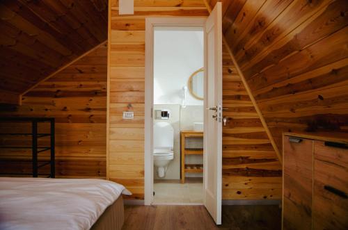 SohodolZenit Chalet Sohodol-Bran的一间带木墙的卧室和一间带卫生间的浴室