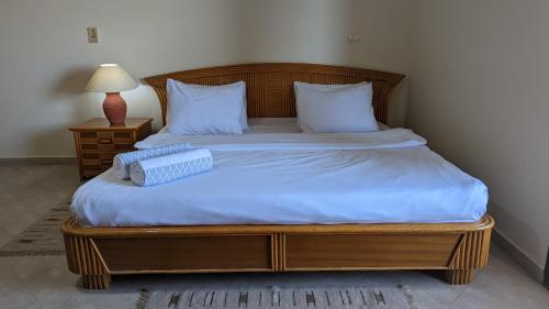 沙姆沙伊赫Golf Heights Sea and Mountain View Studio with Free Wi-Fi的一张带木架、白色床单和枕头的床