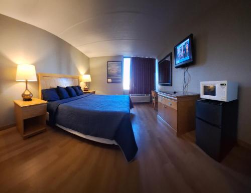 麦迪逊Madison Inn & Suites的一间卧室配有蓝色的床和电视