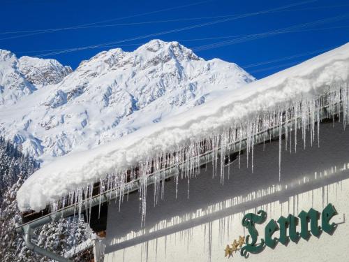 圣安东阿尔贝格打谷场酒店的雪覆盖的屋顶上,有冰雪覆盖的山