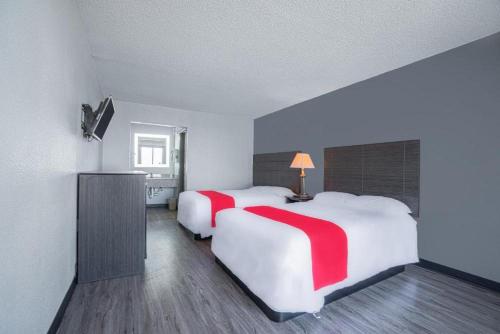 特克萨卡纳StateLine Stayovers Extended Stay Hotel的酒店客房配有两张红色床铺。
