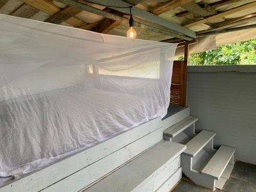 卡瓜斯Camping para dos - a escoger segun disponibilidad de caseta o cabaña的白色床单的带顶棚门廊内的一张床位