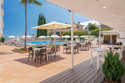 丰沙尔Estrelicia Hotel的一个带桌椅的庭院和一个游泳池