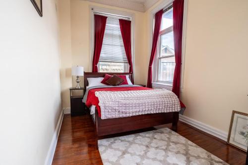 巴尔的摩Cozy historic 3rdfl apartment的一间卧室配有床和两个带红色窗帘的窗户。