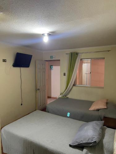 卡拉马Alojamientos OPV的一间卧室设有两张床、一个窗口和电视