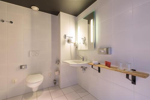 阿尔梅勒Leonardo Hotel Almere City Center的一间带卫生间、水槽和镜子的浴室