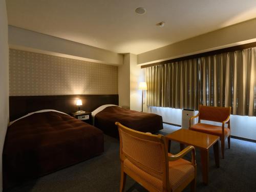 SabaeSabae City Hotel的酒店客房带两张床和一张桌子以及椅子。