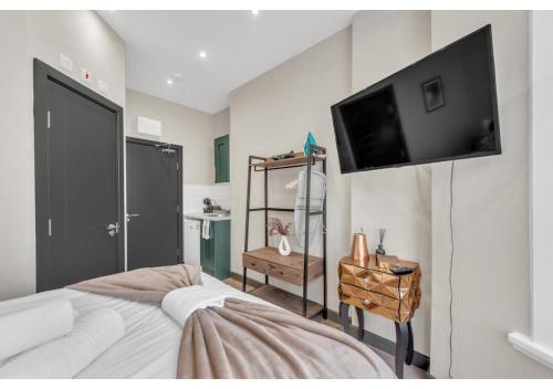 伦敦Escape the Ordinary: Cozy and Charming Studio的一间卧室配有一张床和一台平面电视