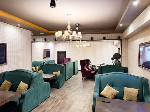 阿斯塔纳REIKARTZ PARK ASTANA ex-Royal Park Hotel & SPA的一间设有绿色桌椅和吊灯的餐厅