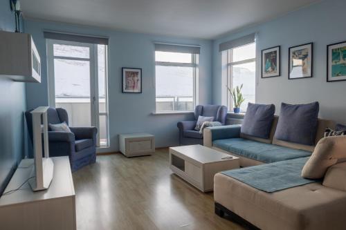内斯考塔杜尔希尔迪布兰德公寓酒店的客厅拥有蓝色的墙壁,配有沙发和椅子