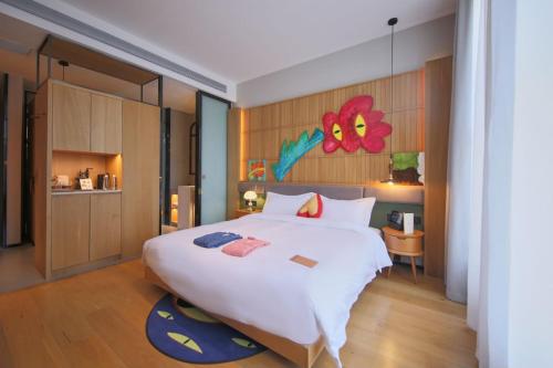 上海上海光时旅行酒店的卧室配有一张白色大床,墙上挂着鲜花