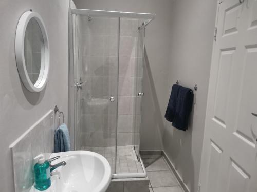 圣约翰港Amapondo Backpackers Lodge的带淋浴、盥洗盆和镜子的浴室