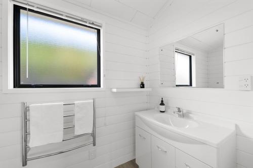 HaruruPaihia Coastal 2 Bedroom Cottages的白色的浴室设有水槽和窗户。
