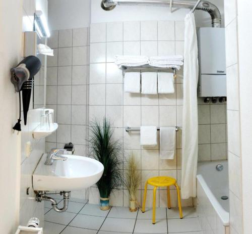 亚琛劳兹贝格酒店的白色的浴室设有水槽和黄色凳子