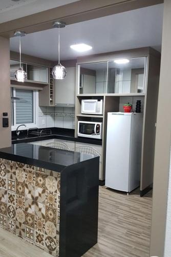 孔塔任recanto do aconchego的厨房配有黑色柜台和白色冰箱。