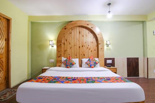 VashishtFabHotel River Bank的一间卧室配有一张大床和木制床头板