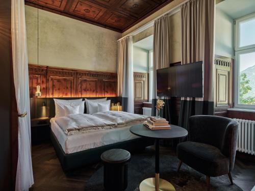 巴德加斯坦Straubinger Grand Hotel Bad Gastein的一间卧室配有一张床、一张桌子和一台电视。