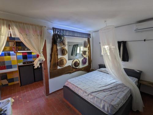 NdanganeLa Maison Blanche的一间卧室配有一张床,墙上挂有镜子和帽子