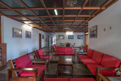 塞拉Praia Sol Hotel by Castelo Itaipava的一间设有红色椅子和桌子的等候室