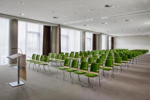 布雷达IntercityHotel Breda的一间会议室,配有绿色椅子和讲台