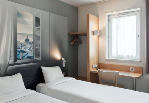 诺伊斯·勒·格兰德B&B HOTEL Noisy-le-Grand的酒店客房设有两张床、一张书桌和一个窗户。