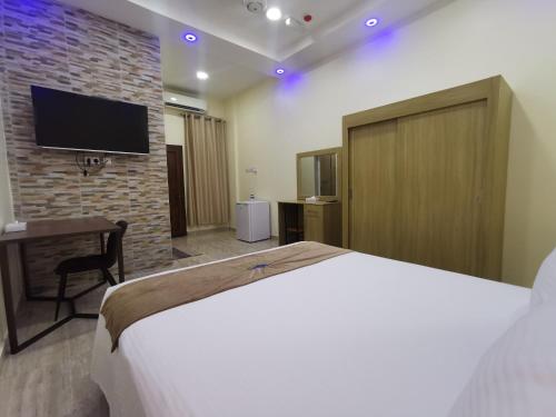 索哈尔Sohar Hotel - فندق صحار的卧室配有1张床和1台砖墙电视