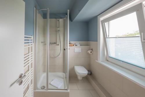圣彼得奥尔丁Hotel 'Das Strandhaus'的带淋浴和卫生间的浴室以及窗户。