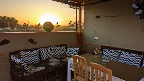 卢克索Yasmine Guest House的餐厅设有桌椅,享有日落美景